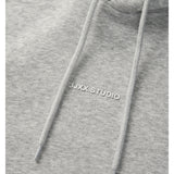 Detaljefoto af fronten på en Studio Vesterbro hoddie i lysgrå, hvor man ser skriften JJXX STUDIO. Fra BySofieSønderby
