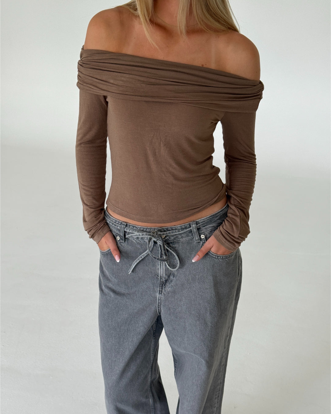 Modelbillede af TARA off shoulder bluse, brun og EDA wide leg jeans, grå. Begge fra BySofieSønderby