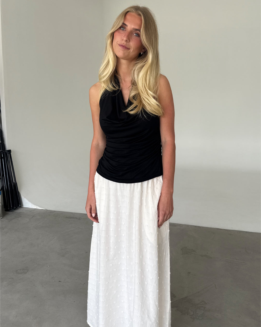 Modelfoto af pige som bærer en sort TAYLOR halterneck top, samt hvid nederdel. Alt er fra BySofieSønderby