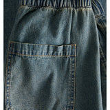 Baglomme af denimshorts med elastisk talje ses tæt på, viser denimvævningens blå farve og robuste syninger i et enkelt, afslappet design.
